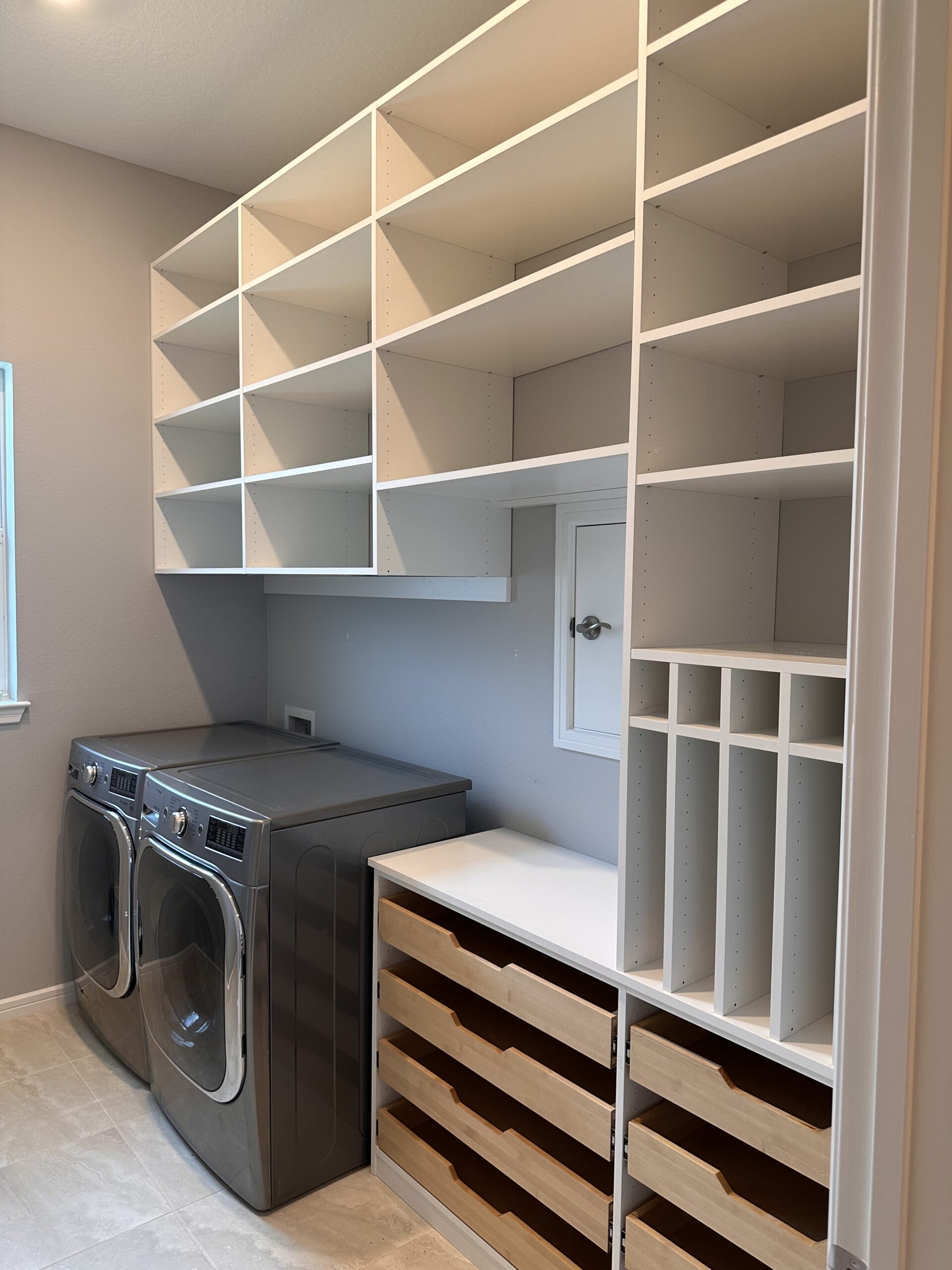 Laundry with white shelving and wood drawers