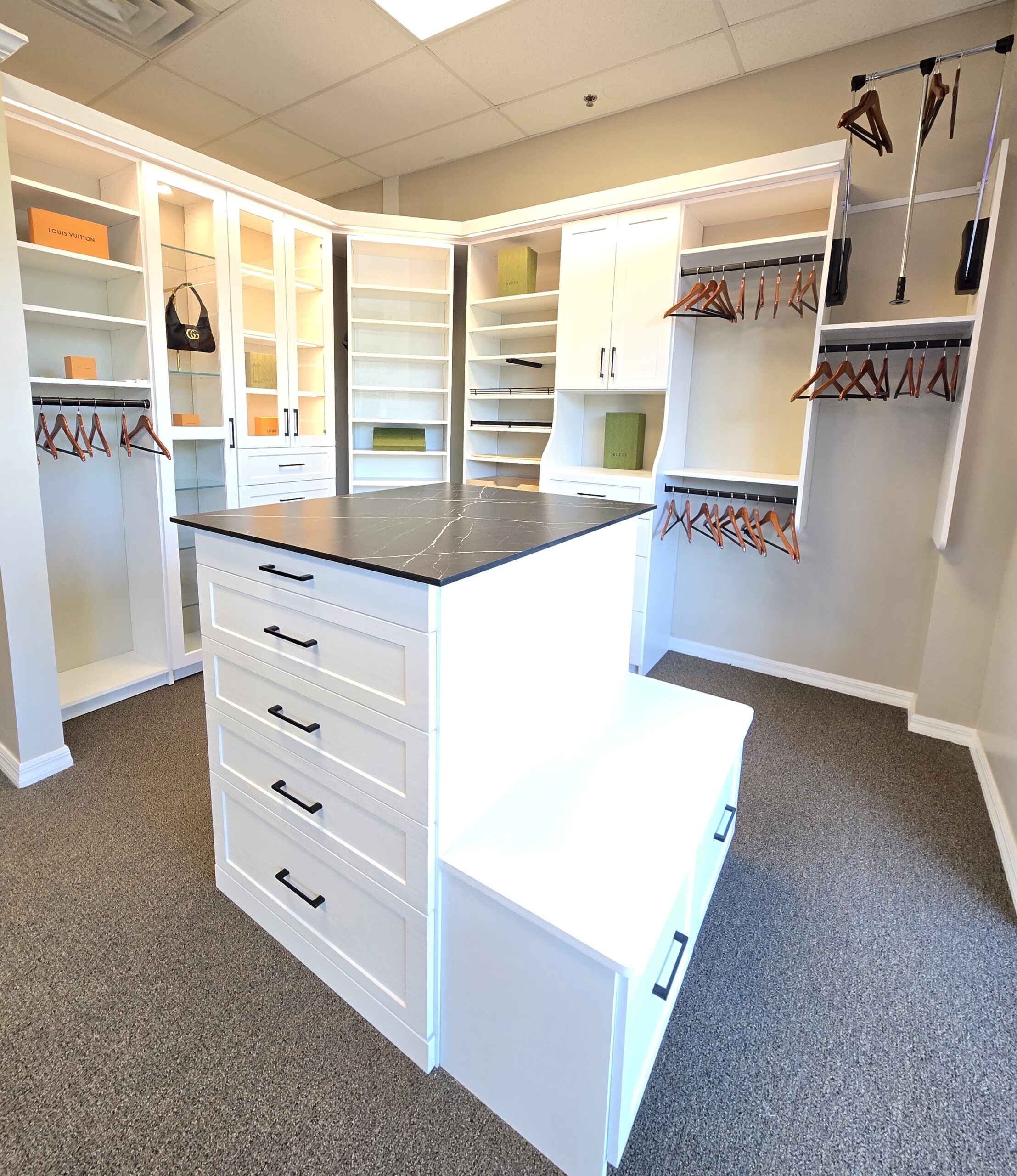 Luxury aisle-style walk-in closet in light oak with pull-down wardrobe bars, LED strip ceiling lighting, and built-in valet accessories